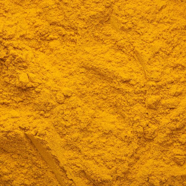 A close-up texture shot of bright yellow-orange ground turmeric powder filling the entire frame.