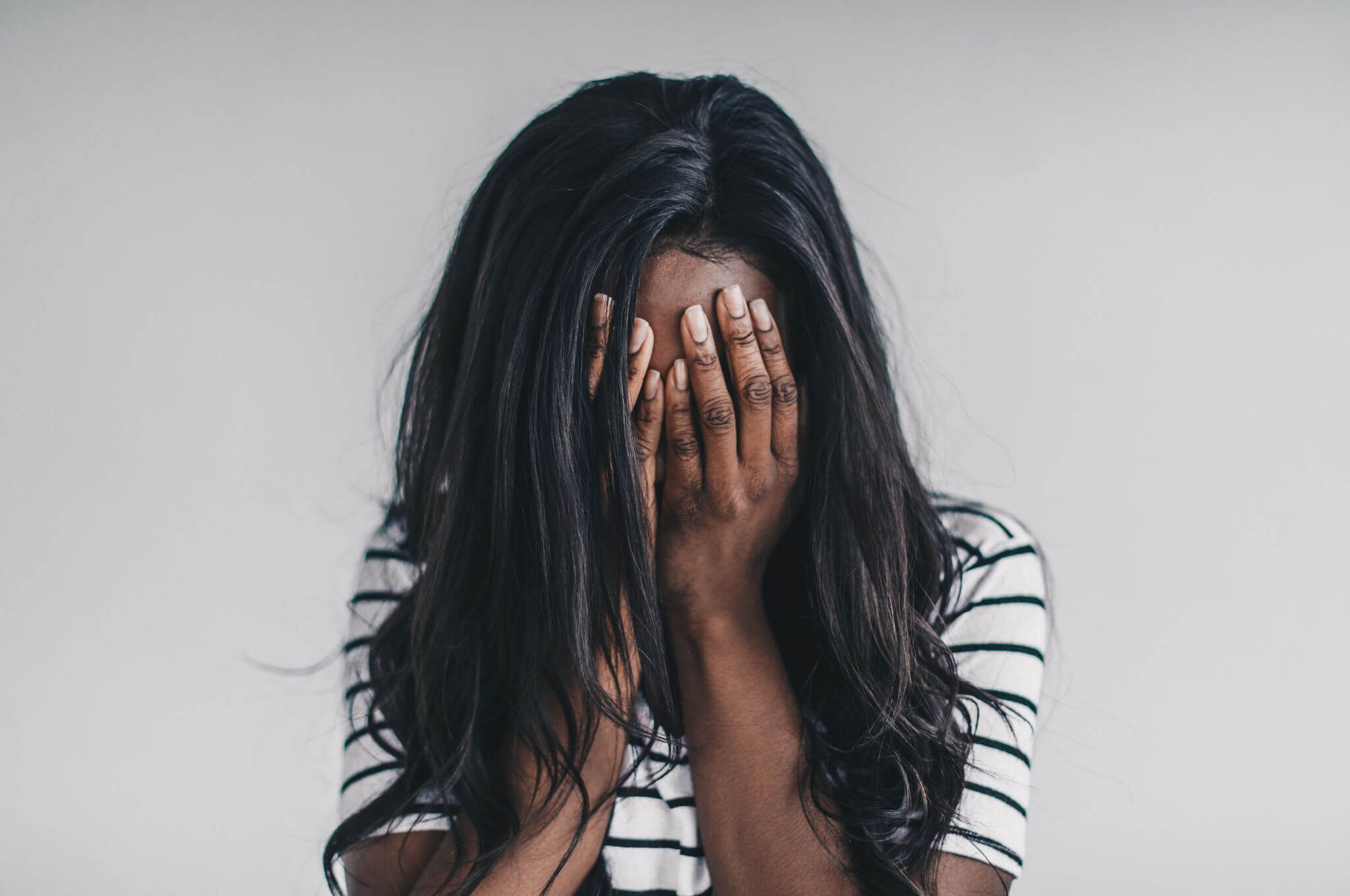 A lady presses her head into her hands in a moment of stress.